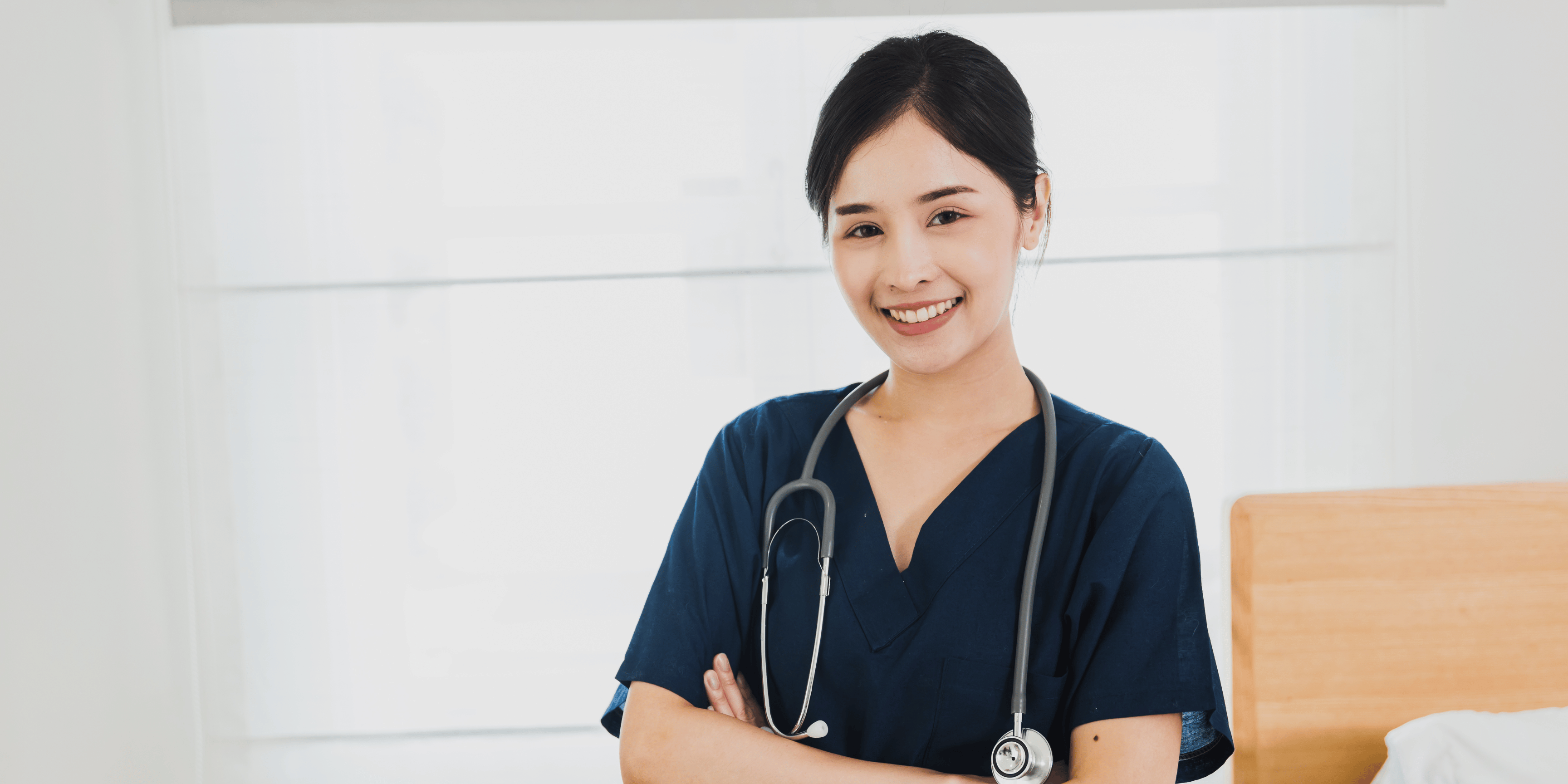 Confident looking nurse with a big smile on her face, and wearing dark blue scrubs