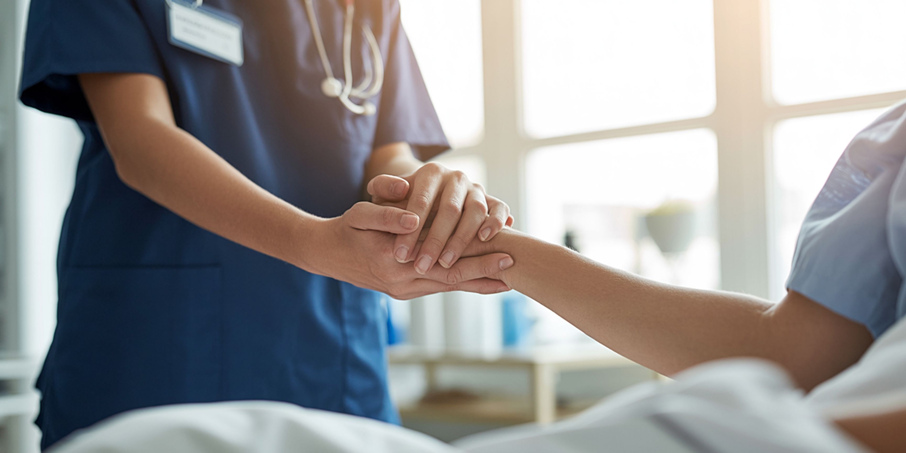 Nurse holding patients hand to offer them comfort in this difficult time in their life