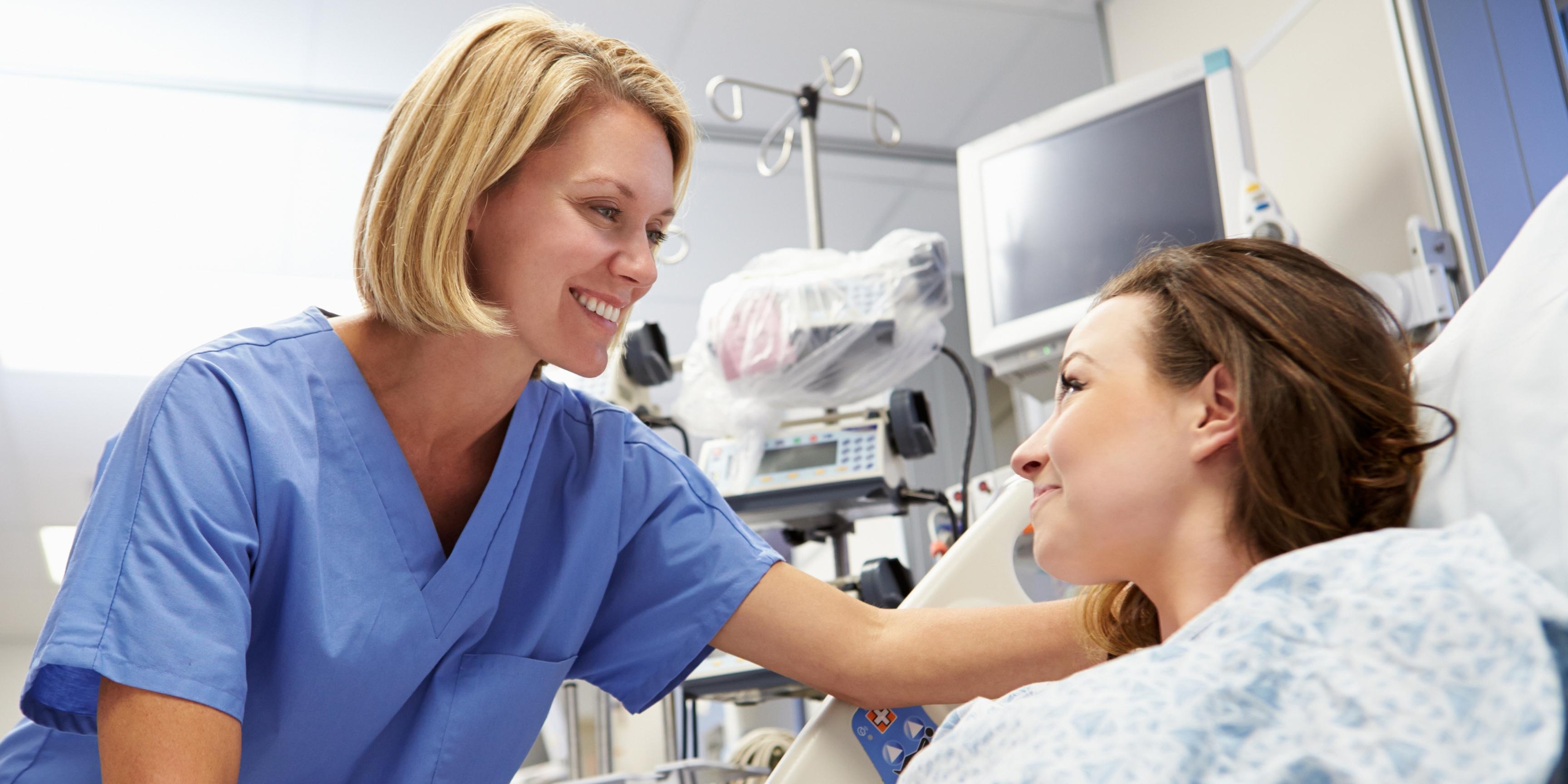 Nurse offering patient reassurance as they lay in the emergency unit